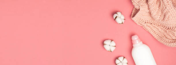 istock Eco cleaning concept. White plastic packaging of laundry detergent, liquid powder, washing conditioner, knitted wool sweater, cotton flowers on pink background. Flat lay top view. Bio organic product 1387815030