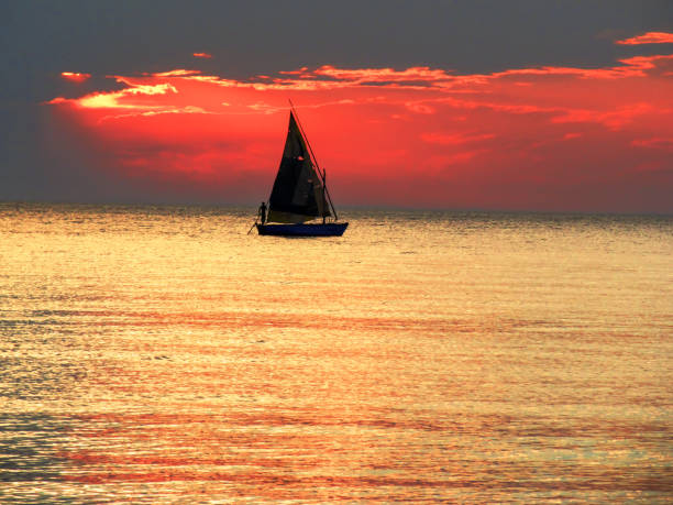 A spectacular sunset with a dhow in silhouette, in Maputo Bay, as seen from the Inhaca Barrier Island System, South Africa stock photo