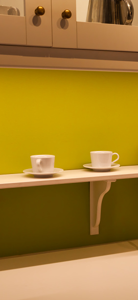 Coffee cup on wooden table. Yellow wall background.