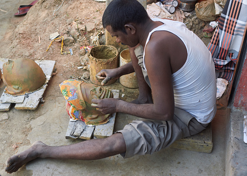 Charida, Purulia, West Bengal, 03-13-2022: An artisan concentrating on applying wet clay, during making of mask for 'Chhau' (the famous masked folk dance of rural Bengal), mostly made from paper pulp and clay. Charida artisans have mastered this art.
