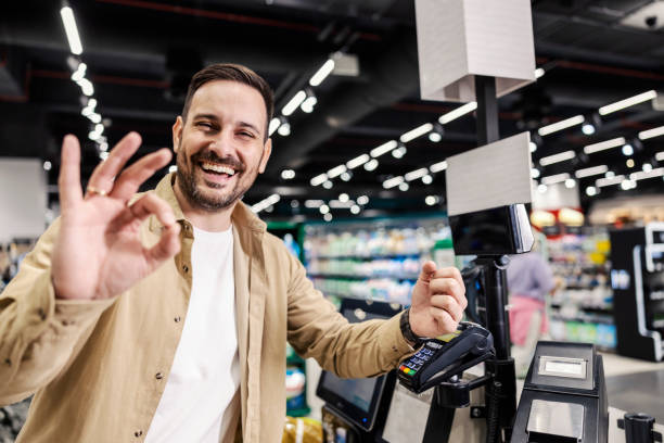 istock Happy man paying with smart watch app in grocery store. 1387826436