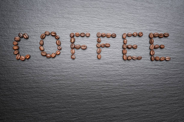 istock The inscription Coffee is lined with coffee beans. Rough grey stone background 1387827648