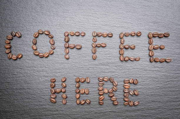 istock The inscription Coffee here is lined with coffee beans. Rough grey stone background 1387833092