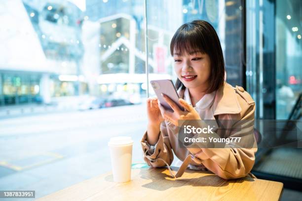 喫茶店でスマホを使うアジアの若い女性