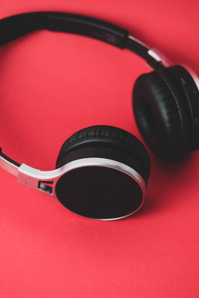 istock Black earphones on a red background 1387835130