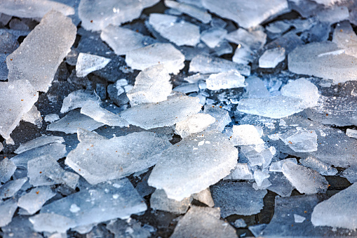 Shards of broken ice on sidewalk. View from above. Cleaning sidewalk and footpaths from icing.