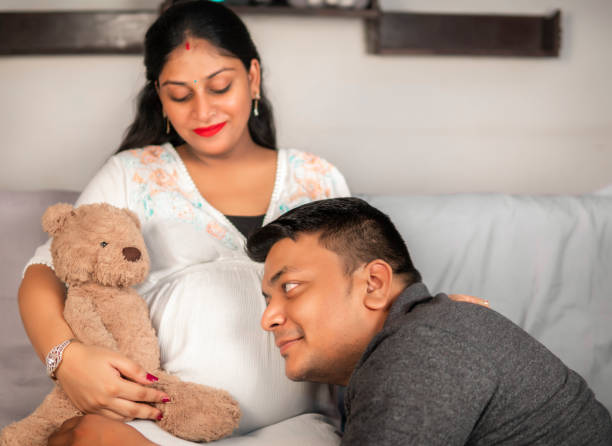 feliz hombre indio sosteniendo el vientre de su hermosa esposa embarazada. - baby shower women home interior indoors fotografías e imágenes de stock