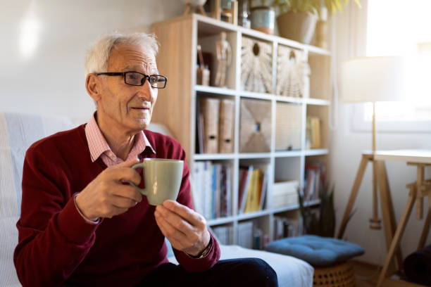 istock Serene senior man watching TV while holding cup of tea 1387836244