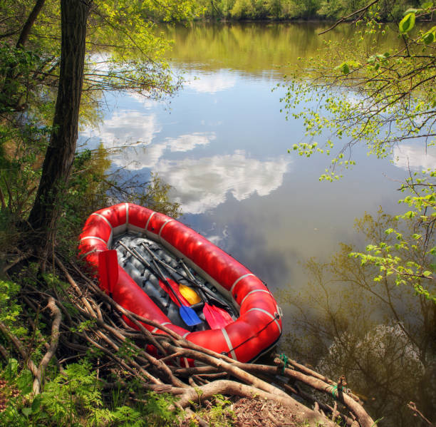 istock Red inflatable boat with oars (raft) for rafting along a  river against the sky reflected in the water. View from above 1387838704
