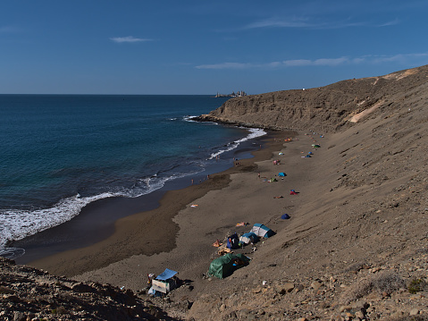 Beautiful view over remote sand beach Playa Montana Arena near Pasito Blanco on the southern coast of Gran Canaria, Canary Islands, Spain with people enjoying the winter sun.
