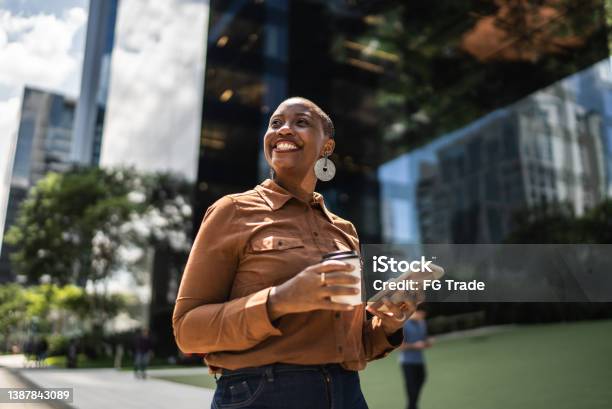 Business Woman Holding Smartphone And Looking Away Outdoors Stock Photo - Download Image Now