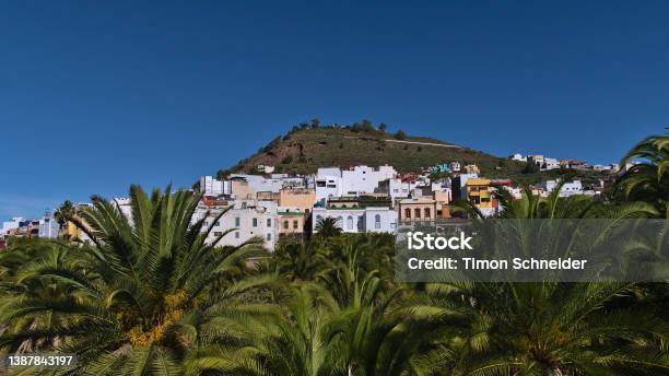 View Of Characteristic Residential Buildings In Town Arucas In The North Of Gran Canaria Canary Islands Spain On Sunny Day With Hill And Green Palm Trees In Front Stock Photo - Download Image Now