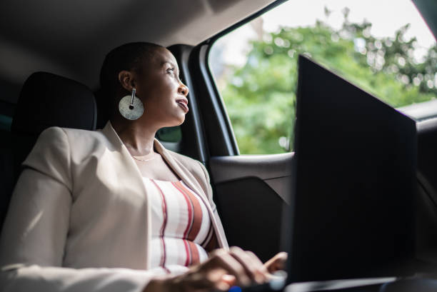 donna d'affari che guarda attraverso il finestrino in una macchina - taxi travel business women foto e immagini stock