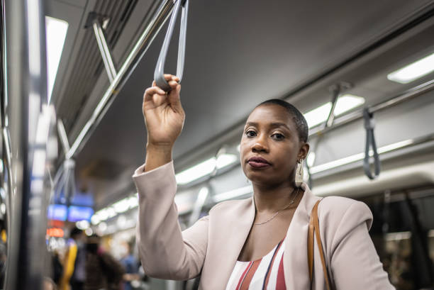 retrato de una mujer adulta sosteniendo la empuñadura en el tren subterráneo - real people waist up looking at camera vertical fotografías e imágenes de stock