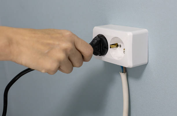 istock a woman's hand sticks a power cord into an electrical outlet 1387843652