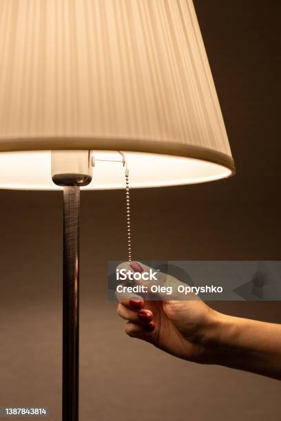 Lamp Night Light By The Rope Which The Hand Pulls Stock Photo - Download Image Now - Turning On Or Off, Electric Lamp, Lighting Equipment