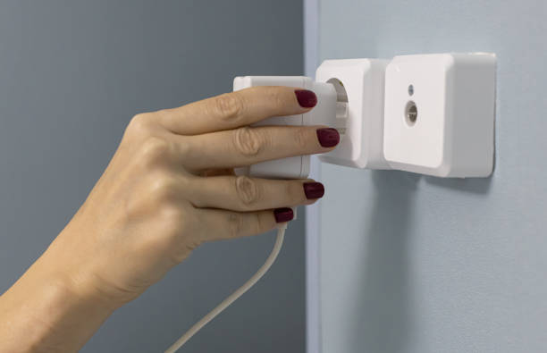 istock a female hand sticks the power supply into the socket 1387844769
