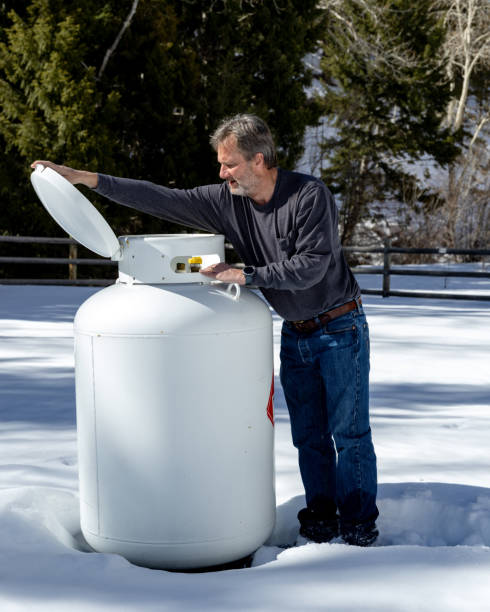 istock Outdoors in winter map opens lid of large propane tank to begin maintenance 1387844865