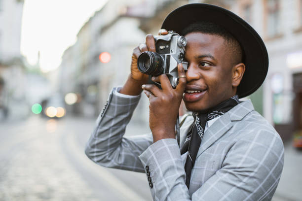istock African man taking photo on retro camera while walking 1387852492