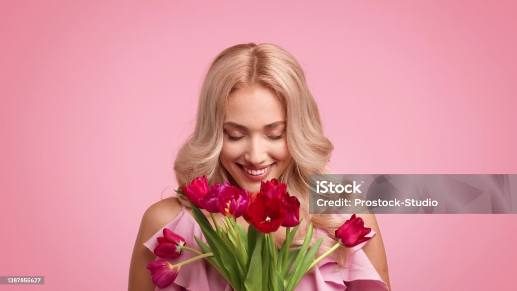 Happy Blonde Female Holding Bouquet Of Tulips Over Pink Background Happy Blonde Female Holding Bouquet Of Tulips Smiling To Camera Celebrating Women's Day Posing Standing Over Pink Background. Spring Holidays And Flowers Delivery. Studio Shot Number 8 Stock Photo