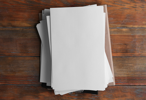 Stack of blank paper sheets on wooden background, top view