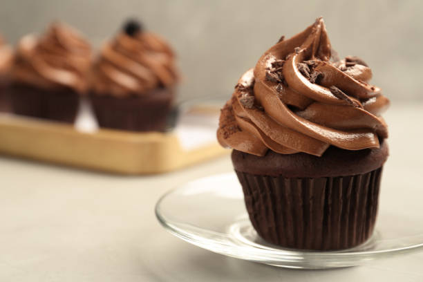 istock Delicious chocolate cupcake with cream and crumbles on light grey table, closeup. Space for text 1387858732