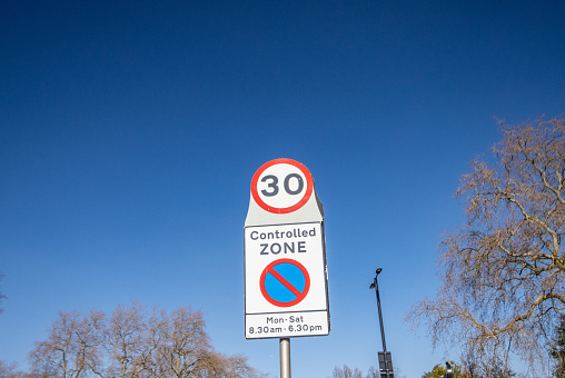 School zone reminder sign against blue sky with white clouds