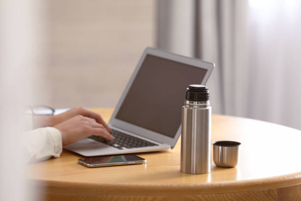 istock Woman with thermo bottle working at table in modern office, closeup 1387859344