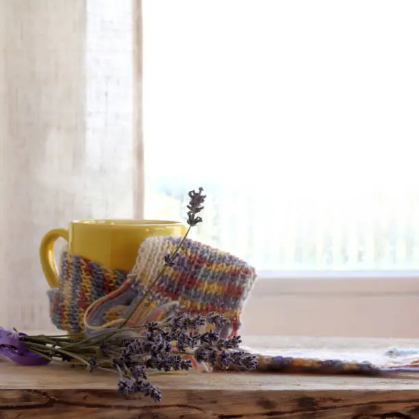 mug in a scarf with a bouquet of lavender on a table by the window