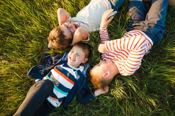istock School-age boys lie on the grass. 1387862415