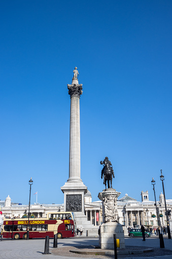 A sightseeing bus drives past the Charles I Monument (cast in 1633 by Hubert Le Sueur and erected in this position in 1675) and Nelson's Column (built by 1843 to a design by William Railton).