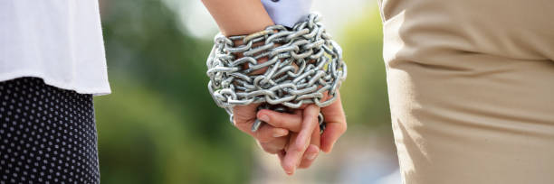 Couple's Hand Tied With Metal Chain Rear View Of Couple's Hand Tied With Metal Chain At Outdoors co dependent relationship stock pictures, royalty-free photos & images