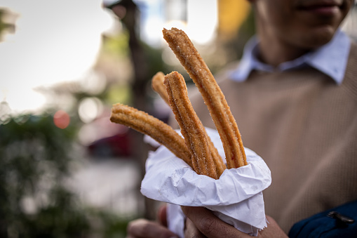 Close up photo of churros, selective focus, unknown man holding churros