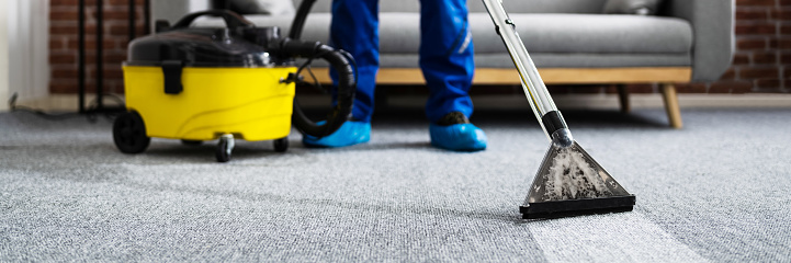 Janitor Cleaning Carpet With Vacuum Cleaner At Home