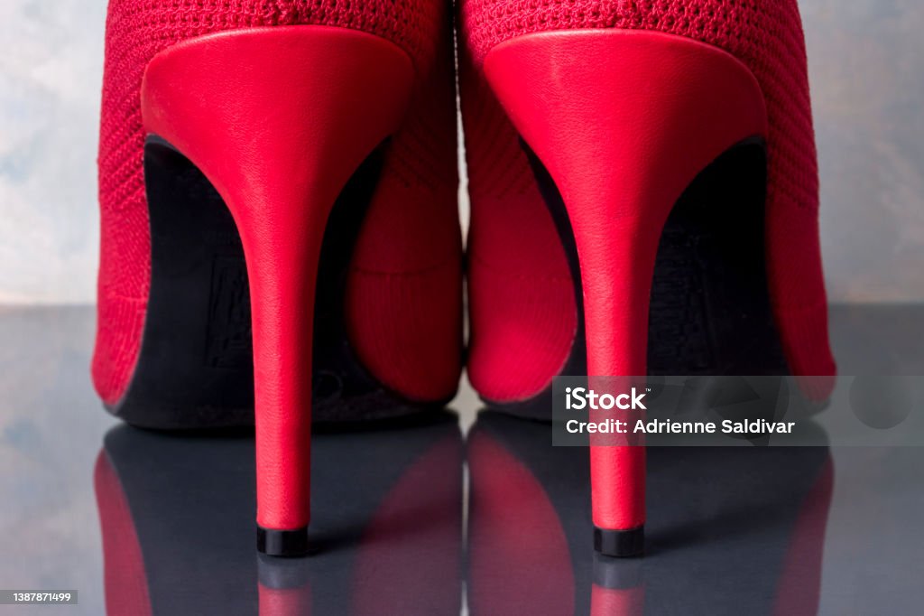 Red stiletto heel boots A pair of bright red stiletto heel boots with black soles, close-up of back view, on a gray background and reflected in a shiny surface. Boot Stock Photo