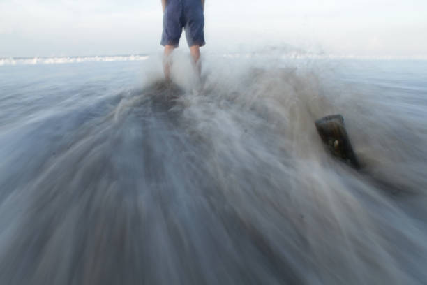 Balancing on the rocky shoreline, a man enjoys the solitary pursuit of fishing, his silhouette a testament to the tranquility and focus of this outdoor pastime.