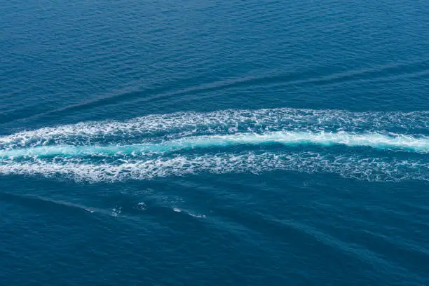 trail of a motor boat in blue sea water, relaxing boat trip on the blue Mediterranean Sea, travel and aquatic sports, blue background