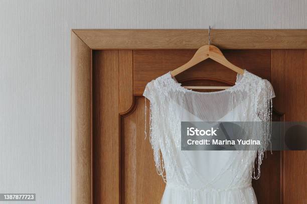 The Wedding Dress Is Hanging On A Hanger On The Door Stock Photo - Download Image Now