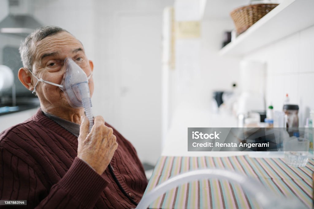 Senior man doing inhalation with nurse at home Adult Stock Photo