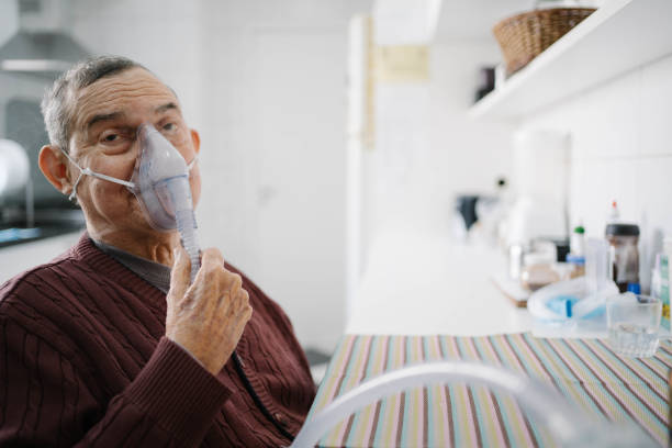 Senior man doing inhalation with nurse at home stock photo
