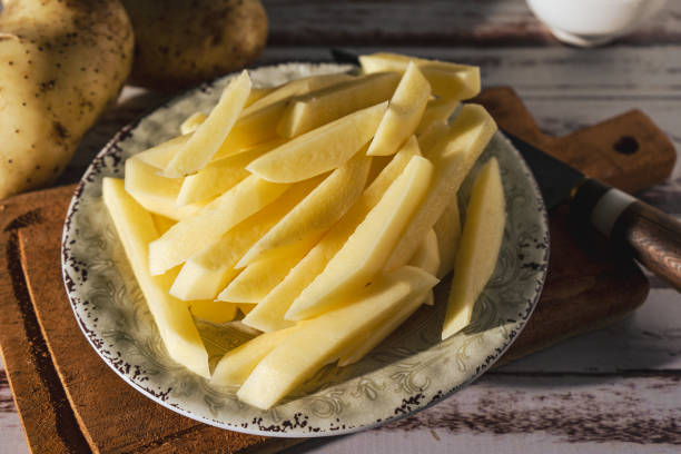 plat avec des pommes de terre de canne crues pour faire des frites français. vue hachée ou haute. - french fries fast food french fries raw raw potato photos et images de collection