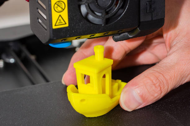 Close-up of man hands taking finished 3D printed model of yellow PLA ship. Detail of printhead with fan and hotend. Close-up of man hands taking finished 3D printed model of yellow PLA ship. Detail of printhead with fan and hotend 3d printing hand stock pictures, royalty-free photos & images