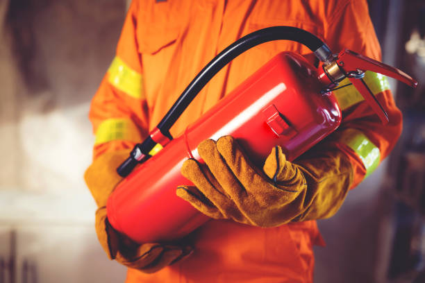 istock Fireman hand holding fire extinguisher. available in emergencies conflagration damage background. Safety concept. 1387901954