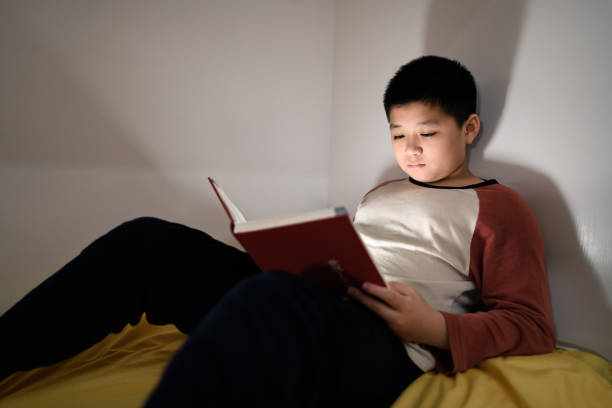 istock A handsome Asian boy reading in bed. 1387909141