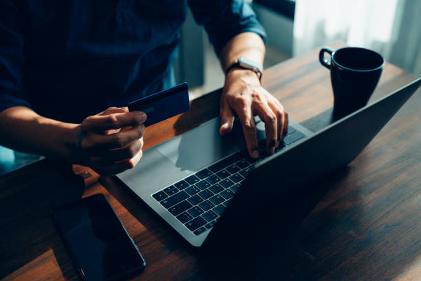 istock Businessman hand holding credit card and using laptop 1387912922