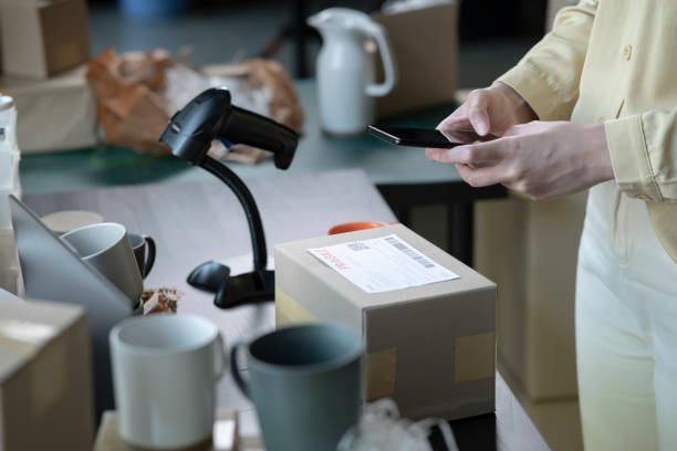 istock Female small business owner using mobile app on smartphone checking parcel box. 1387918188
