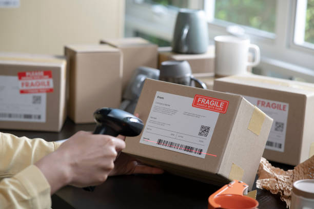 istock Woman working in factory warehouse scanning labels on the boxes with barcode scanner. 1387918201