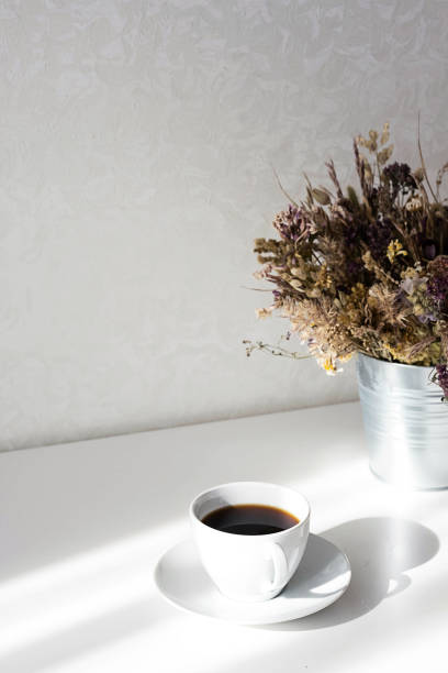 istock Aromatic black coffee cup on white table with interesting shadows.Scandinavian style still life in the morning rays of sun. 1387933165