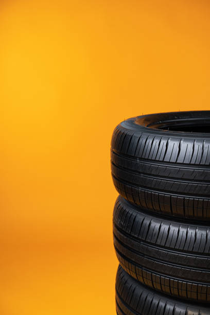 istock Car tires isolated on yellow background, close up 1387936047