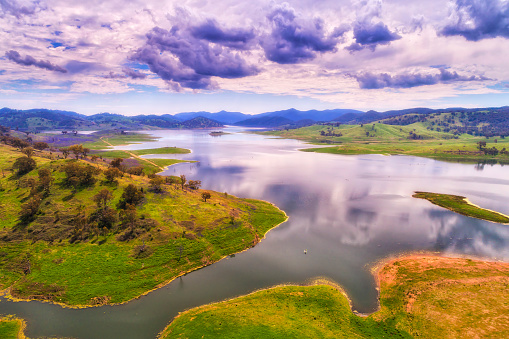 Lake Windamere on Cudgegong river with small fishing boat in green hilly regional of NSW, Australia - aerial panorama.